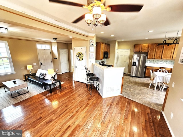 kitchen with stainless steel refrigerator with ice dispenser, ceiling fan, tasteful backsplash, light hardwood / wood-style floors, and kitchen peninsula