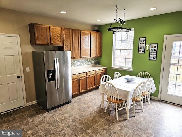 kitchen featuring tasteful backsplash, hanging light fixtures, and stainless steel refrigerator with ice dispenser