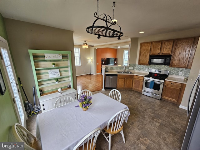 kitchen featuring pendant lighting, sink, ceiling fan, decorative backsplash, and stainless steel appliances