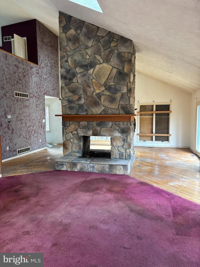 unfurnished living room featuring a fireplace, a textured ceiling, hardwood / wood-style flooring, and lofted ceiling