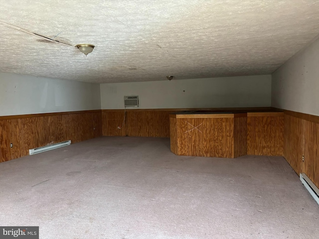 additional living space featuring light colored carpet, a textured ceiling, wooden walls, and a baseboard radiator