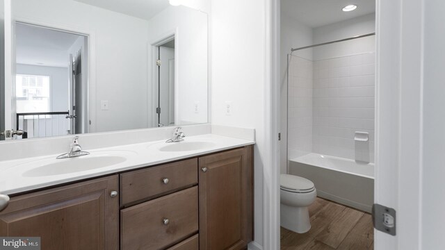 full bathroom featuring hardwood / wood-style floors, vanity, toilet, and shower / bath combination