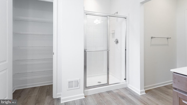 bathroom featuring hardwood / wood-style floors, vanity, and a shower with door