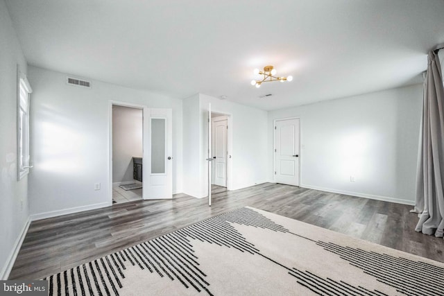 unfurnished room with a chandelier and dark hardwood / wood-style floors