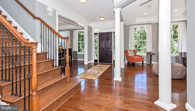 foyer featuring decorative columns, dark wood-type flooring, and ornamental molding