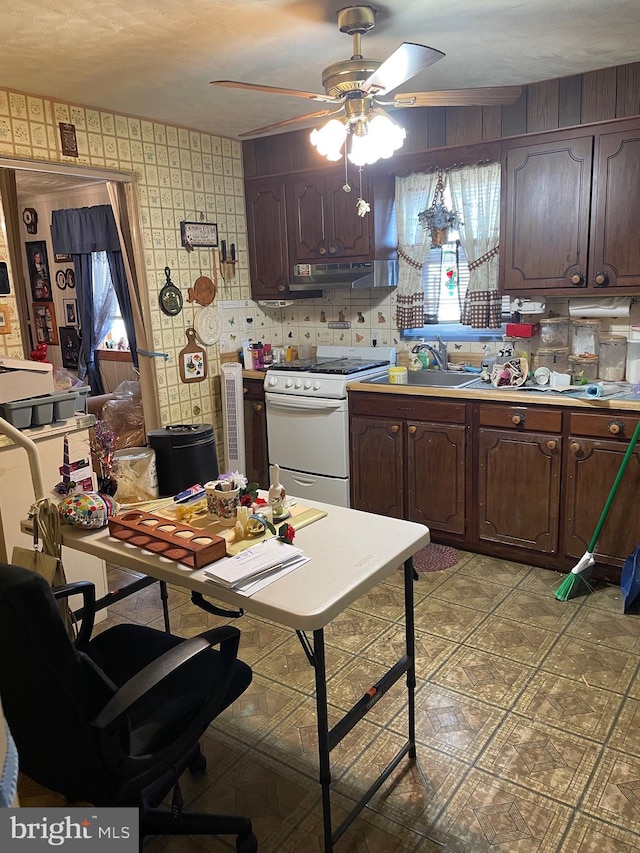 kitchen featuring white range oven, ceiling fan, dark brown cabinets, and sink