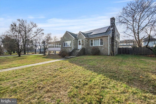 view of front of property featuring solar panels and a front lawn