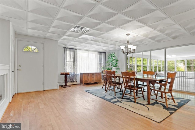 dining area featuring hardwood / wood-style flooring, an inviting chandelier, and a baseboard radiator