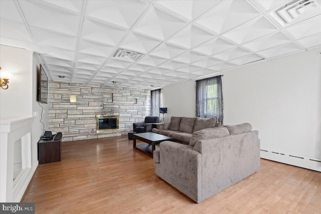 living room with light hardwood / wood-style flooring, a stone fireplace, a baseboard radiator, and coffered ceiling