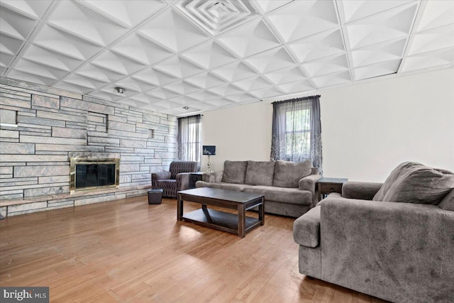 living room with hardwood / wood-style floors, a stone fireplace, and coffered ceiling