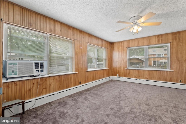 unfurnished room with carpet, a textured ceiling, ceiling fan, and wooden walls