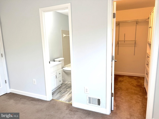 interior space with a walk in closet, carpet floors, ensuite bath, and a closet