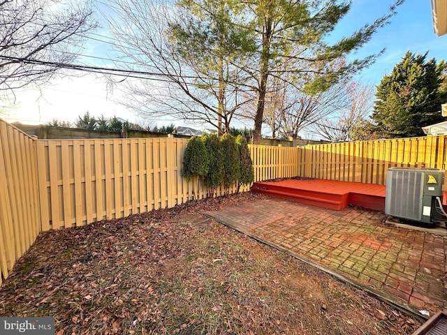 view of yard featuring a patio, a wooden deck, and central AC