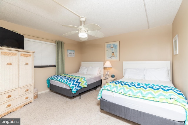 carpeted bedroom featuring ceiling fan and a textured ceiling