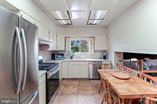 kitchen with backsplash, white cabinets, stainless steel appliances, and light tile patterned flooring