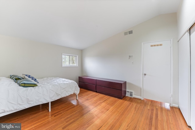 bedroom with lofted ceiling, a closet, and light hardwood / wood-style flooring