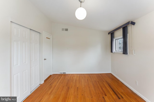 unfurnished bedroom with a closet, lofted ceiling, and wood-type flooring