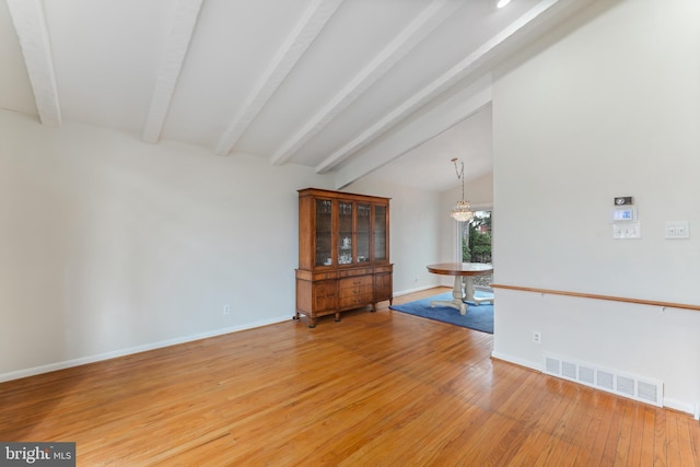 unfurnished room featuring an inviting chandelier, light hardwood / wood-style floors, and lofted ceiling with beams