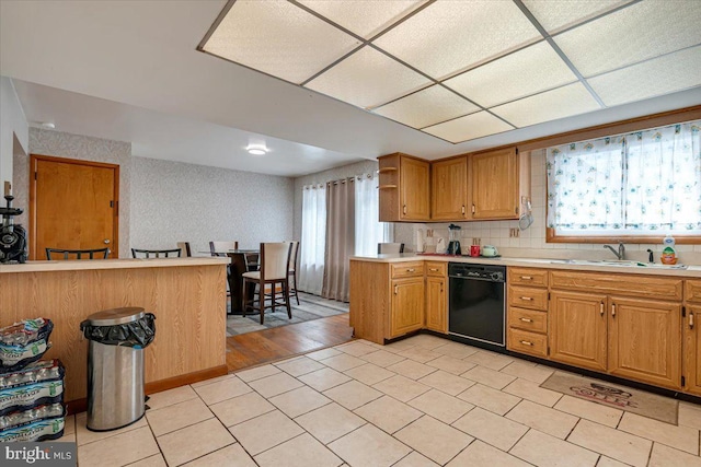 kitchen featuring plenty of natural light, sink, kitchen peninsula, and black dishwasher