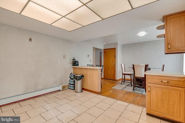 kitchen with kitchen peninsula, light wood-type flooring, and baseboard heating