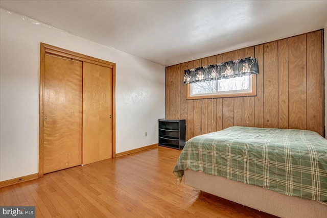 bedroom featuring light wood-type flooring and wooden walls