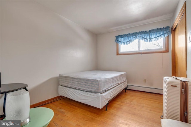 bedroom with baseboard heating and light hardwood / wood-style flooring