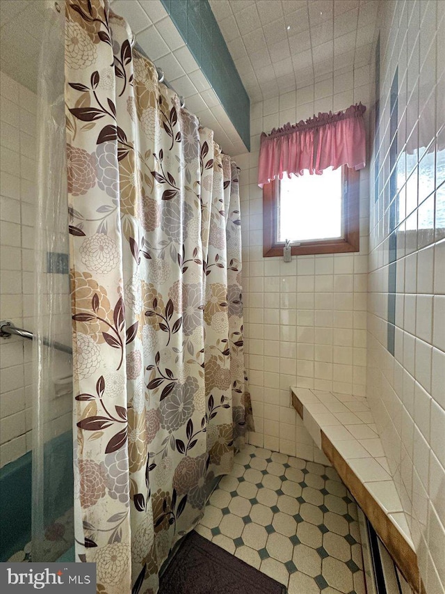 bathroom with a shower with curtain and tile walls