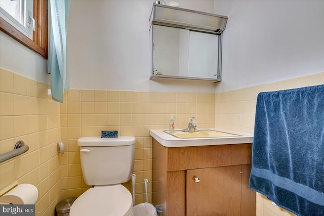 bathroom featuring vanity, tile walls, and toilet