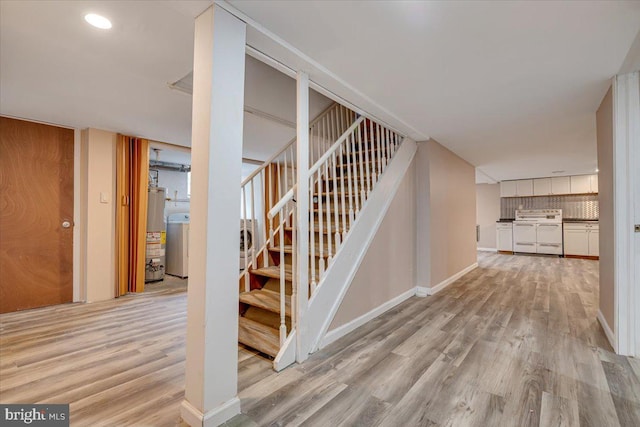 stairway with hardwood / wood-style floors, washer / clothes dryer, and water heater