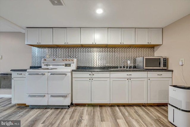 kitchen with white electric range oven, white cabinets, light hardwood / wood-style flooring, and sink