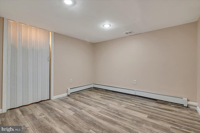 empty room with light wood-type flooring and a baseboard radiator