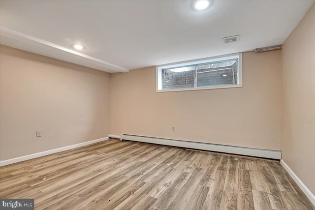 basement with light hardwood / wood-style flooring and baseboard heating