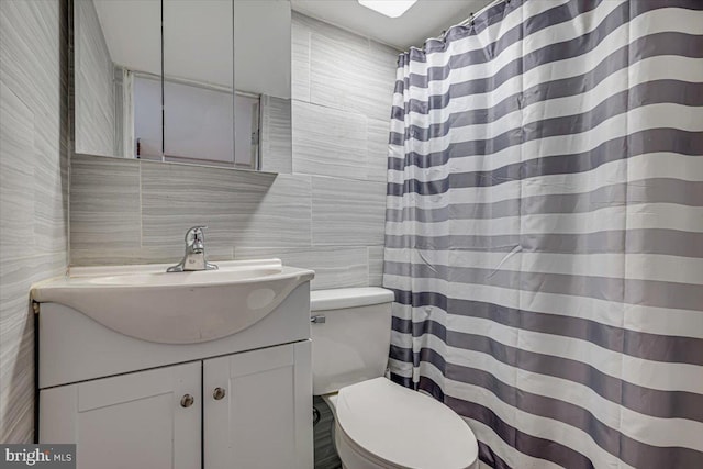 bathroom featuring vanity, toilet, tile walls, and backsplash