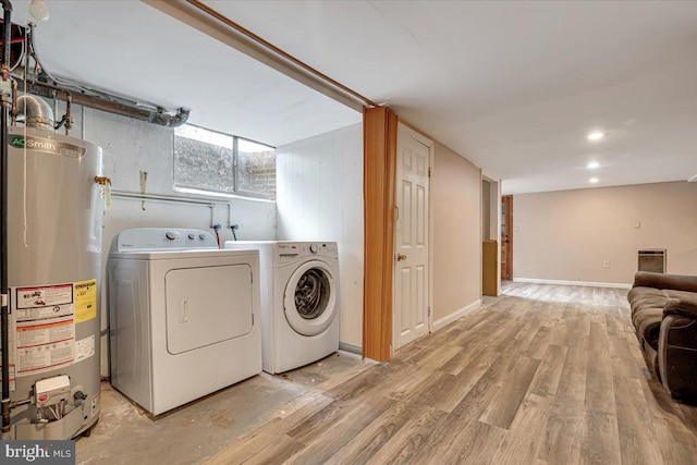 washroom featuring washing machine and clothes dryer, gas water heater, and light wood-type flooring