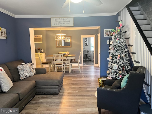 living room featuring ceiling fan with notable chandelier, hardwood / wood-style flooring, a wall mounted AC, and ornamental molding