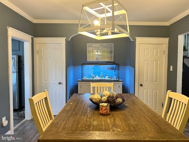 dining area featuring dark wood-type flooring, a notable chandelier, and ornamental molding