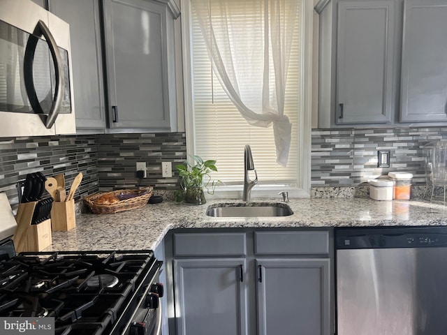 kitchen with tasteful backsplash, light stone countertops, sink, and stainless steel appliances