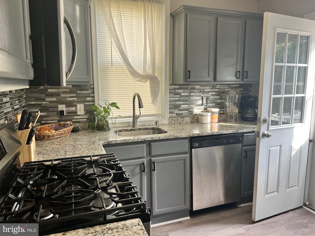 kitchen with dishwasher, gray cabinets, light stone counters, and sink