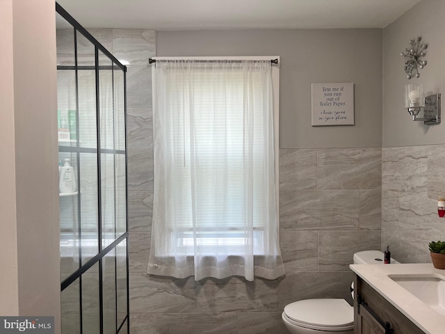 bathroom featuring vanity, toilet, and tile walls