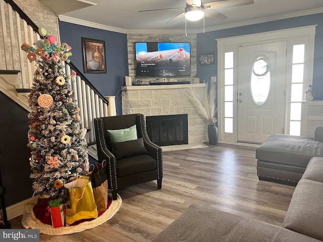 foyer featuring a wealth of natural light, ceiling fan, crown molding, hardwood / wood-style flooring, and a fireplace