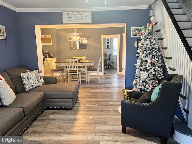 living room featuring wood-type flooring, an inviting chandelier, ornamental molding, and a wall unit AC