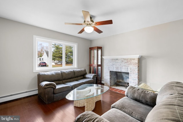 living room with dark hardwood / wood-style floors, ceiling fan, baseboard heating, and a brick fireplace