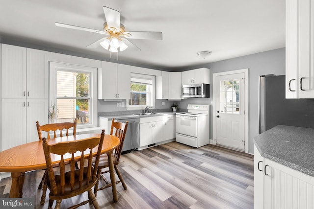 kitchen with appliances with stainless steel finishes, ceiling fan, sink, white cabinets, and light hardwood / wood-style floors