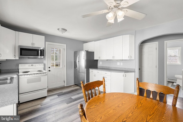 kitchen with appliances with stainless steel finishes, light hardwood / wood-style floors, white cabinetry, and a healthy amount of sunlight