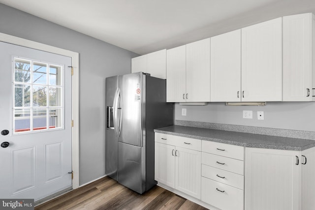 kitchen featuring stainless steel fridge, dark hardwood / wood-style flooring, and white cabinetry