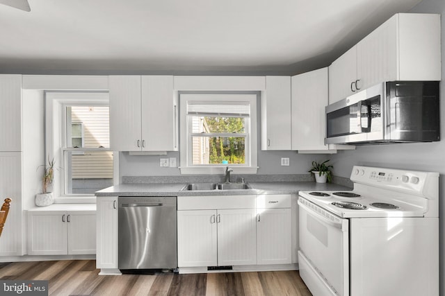 kitchen with hardwood / wood-style flooring, sink, white cabinetry, and stainless steel appliances