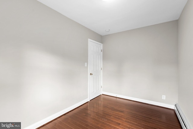 spare room featuring dark wood-type flooring and a baseboard heating unit