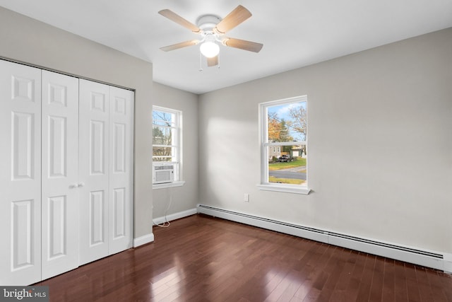 unfurnished bedroom featuring dark hardwood / wood-style floors, baseboard heating, and multiple windows