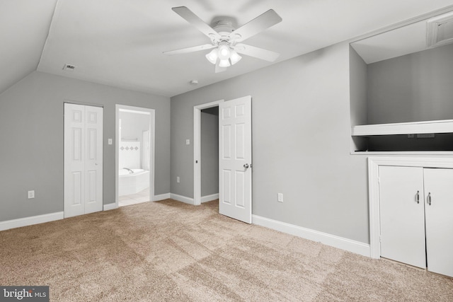 unfurnished bedroom featuring ceiling fan, lofted ceiling, light carpet, and ensuite bath