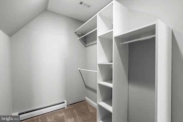 spacious closet featuring dark carpet, baseboard heating, and lofted ceiling